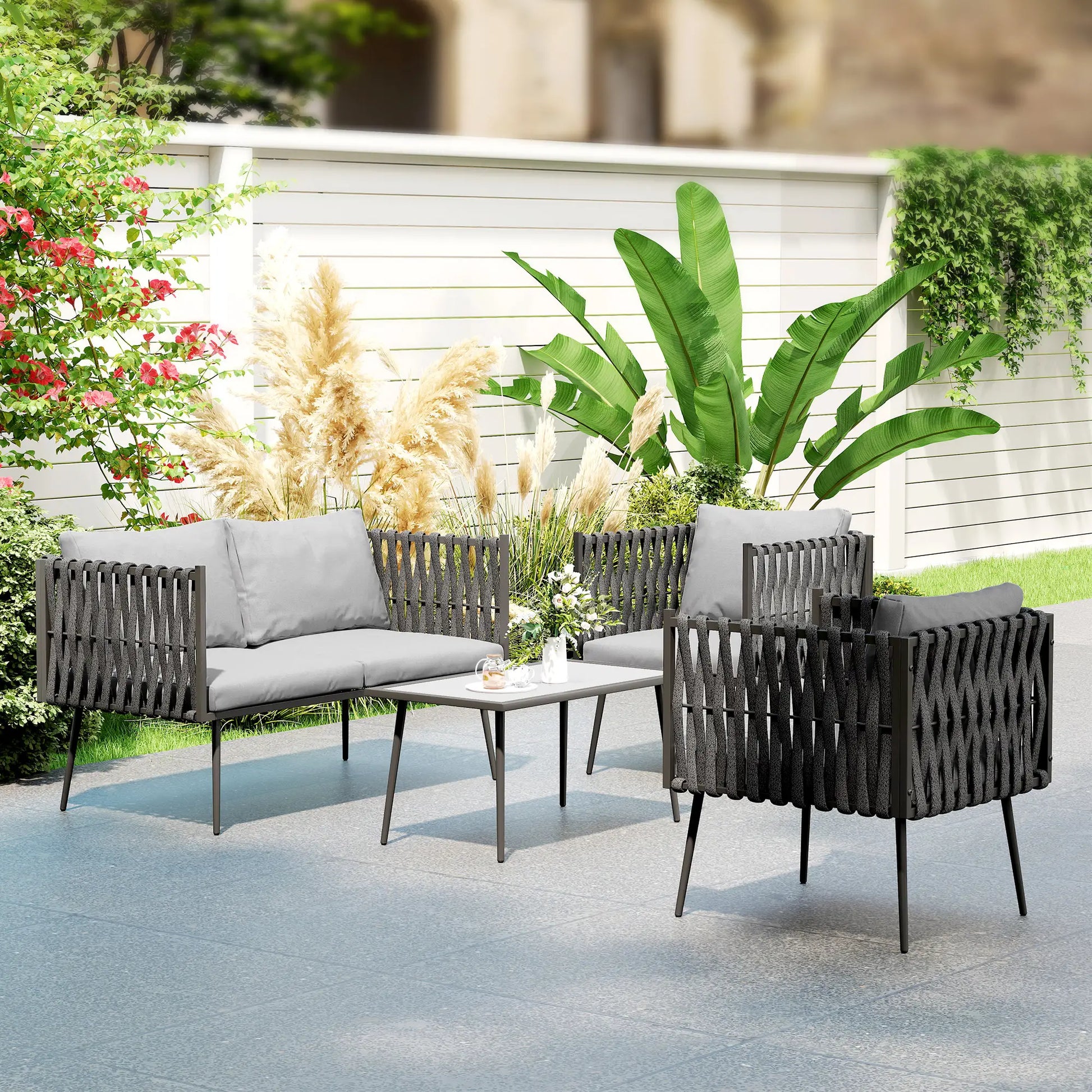 Outdoor patio set with gray cushions and a small table in a garden setting.